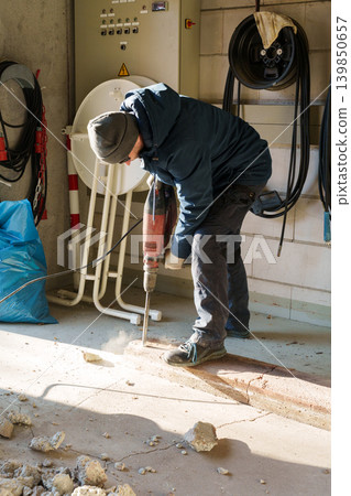 Worker using jackhammer to break concrete floor indoors Worker using jackhammer to break concrete floor indoors 139850657