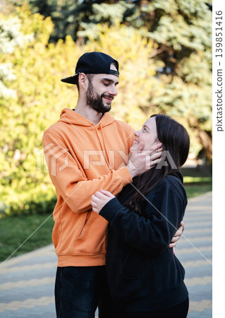 Young Caucasian couple showing affection and emotional connection outdoors while standing together in a sunny park. Love partnership and parenthood lifestyle Young Caucasian couple showing affection and emotional connection outdoors while standing together in a sunny park. Love partnership and parenthood lifestyle 139851416