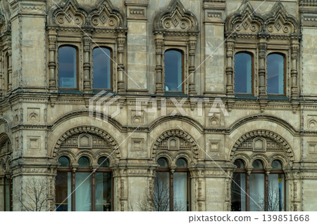 Historic Stone Facade With Ornate Arched Windows And Decorative Architectural Details On Urban Building Historic Stone Facade With Ornate Arched Windows And Decorative Architectural Details On Urban Building 139851668