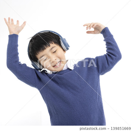 Cheerful boy in headphones singing and dancing Cheerful boy in headphones singing and dancing 139851669