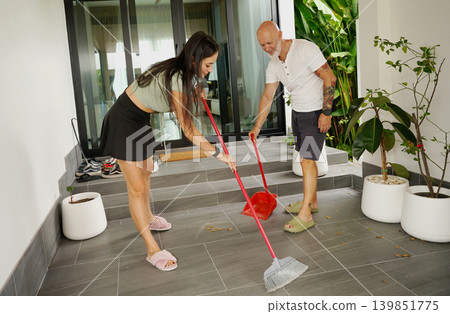 Man and woman enjoy lighthearted cleaning session on their porch during summer Man and woman enjoy lighthearted cleaning session on their porch during summer 139851775