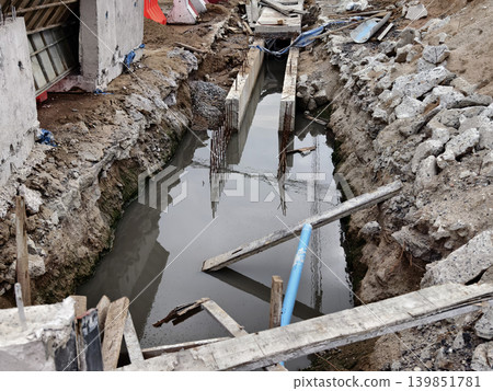 Narrow ditch with reinforcement, waterproof concrete trench bounded by soil and support stakes 139851781