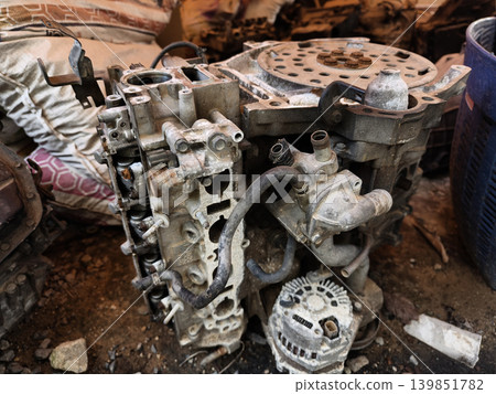 Rusted engine parts and corroded gears scattered across the sandy ground 139851782