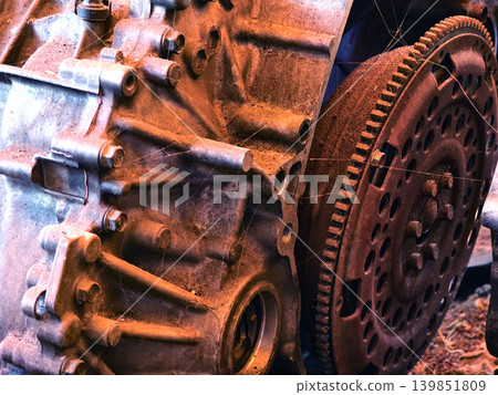 Rusted engine parts and corroded gears scattered across the sandy ground 139851809
