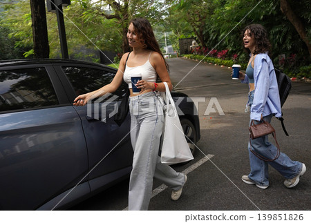 Friends drinking coffee beside their vehicle in bright sunlight Friends drinking coffee beside their vehicle in bright sunlight 139851826