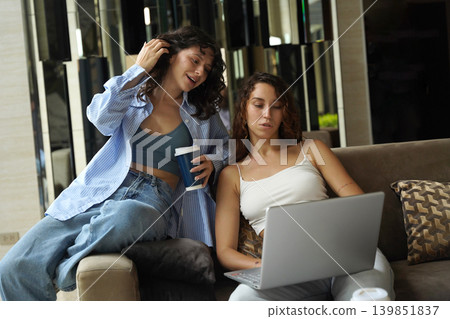 Two young women drink coffee in the co-working office Two young women drink coffee in the co-working office 139851837