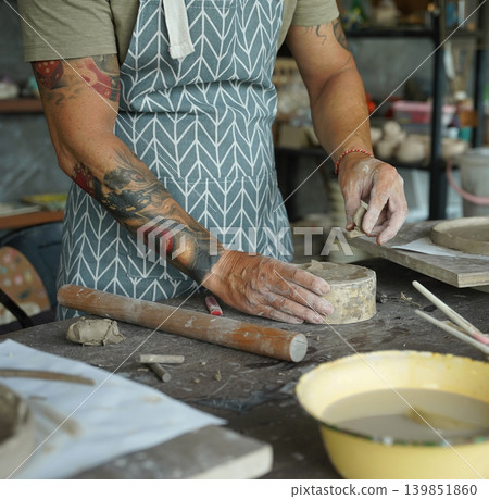 An adult man makes a ceramic plate in a workshop An adult man makes a ceramic plate in a workshop 139851860