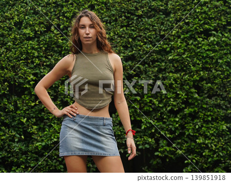 Empowered woman poses against wall with stylish attire 139851918