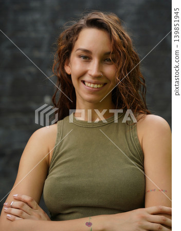Empowered woman poses against wall with stylish attire Empowered woman poses against wall with stylish attire 139851945