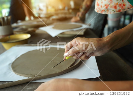 A young woman makes a ceramic plate in a workshop A young woman makes a ceramic plate in a workshop 139851952