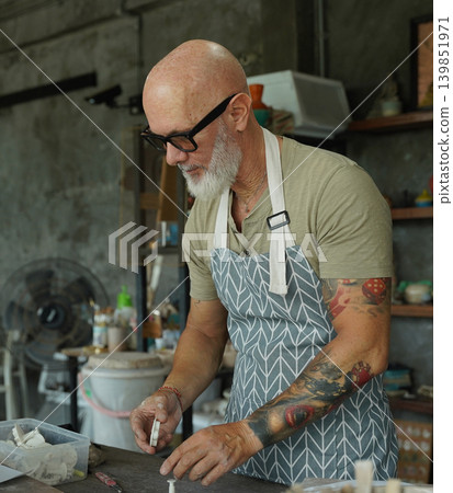 An adult man makes a ceramic plate in a workshop An adult man makes a ceramic plate in a workshop 139851971