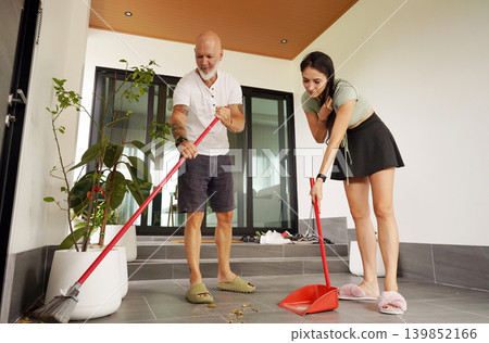 Man and woman enjoy lighthearted cleaning session on their porch during summer Man and woman enjoy lighthearted cleaning session on their porch during summer 139852166