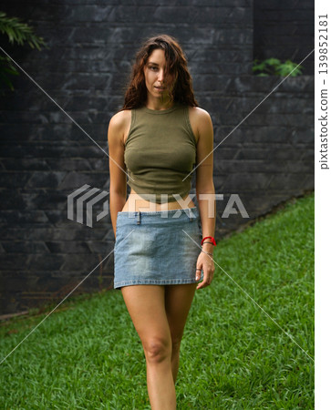 Empowered woman poses against wall with stylish attire Empowered woman poses against wall with stylish attire 139852181