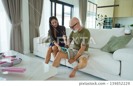A woman helps a man use a massage roller to rehabilitate his knee A woman helps a man use a massage roller to rehabilitate his knee 139852229