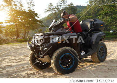 A man engages in extreme ATV riding on sand beach early in the morning A man engages in extreme ATV riding on sand beach early in the morning 139852248