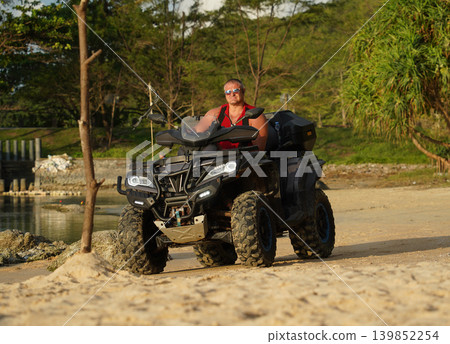A man engages in extreme ATV riding on sand beach early in the morning 139852254