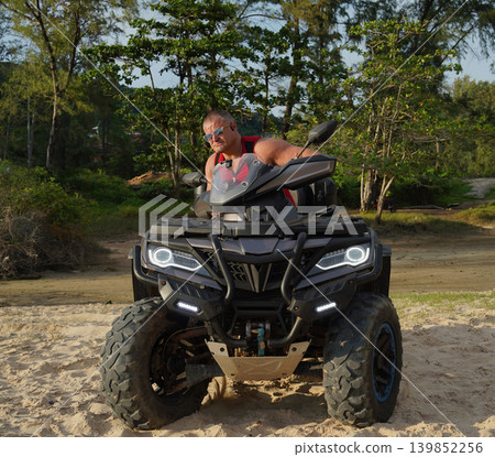 A man engages in extreme ATV riding on sand beach early in the morning A man engages in extreme ATV riding on sand beach early in the morning 139852256