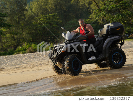 A man engages in extreme ATV riding on sand beach early in the morning A man engages in extreme ATV riding on sand beach early in the morning 139852257