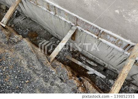 Narrow ditch with reinforcement, waterproof concrete trench bounded by soil and support stakes Narrow ditch with reinforcement, waterproof concrete trench bounded by soil and support stakes 139852355
