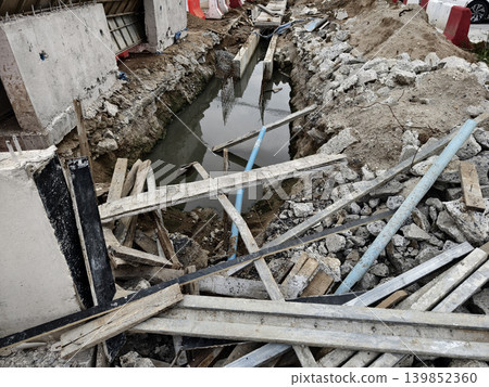 Narrow ditch with reinforcement, waterproof concrete trench bounded by soil and support stakes Narrow ditch with reinforcement, waterproof concrete trench bounded by soil and support stakes 139852360