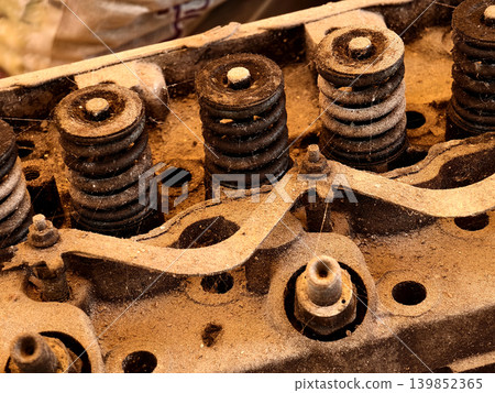 Rusted engine parts and corroded gears scattered across the sandy ground Rusted engine parts and corroded gears scattered across the sandy ground 139852365