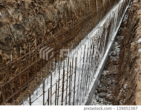 Narrow ditch with reinforcement, waterproof concrete trench bounded by soil and support stakes Narrow ditch with reinforcement, waterproof concrete trench bounded by soil and support stakes 139852367