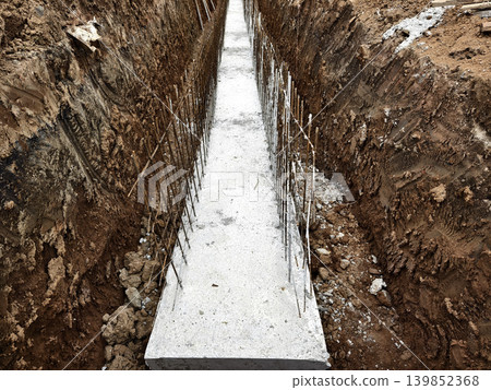 Narrow ditch with reinforcement, waterproof concrete trench bounded by soil and support stakes Narrow ditch with reinforcement, waterproof concrete trench bounded by soil and support stakes 139852368