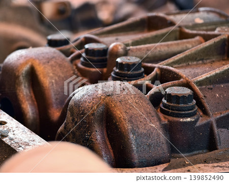 Rusted engine parts and corroded gears scattered across the sandy ground Rusted engine parts and corroded gears scattered across the sandy ground 139852490