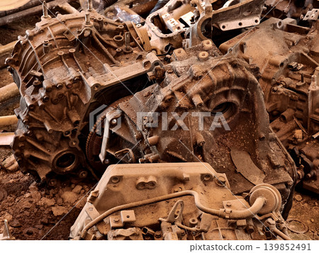 Rusted engine parts and corroded gears scattered across the sandy ground Rusted engine parts and corroded gears scattered across the sandy ground 139852491