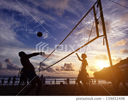 Young people playing beach volleyball by the ocean at sunset Young people playing beach volleyball by the ocean at sunset 139852496