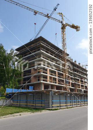 Construction of a multi-storey residential building using construction cranes Construction of a multi-storey residential building using construction cranes 139852592