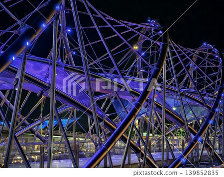 Modern illuminated helix bridge adorned with colorful lights over tranquil waterfront scene Modern illuminated helix bridge adorned with colorful lights over tranquil waterfront scene 139852835