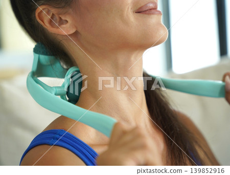 A woman uses a turquoise neck massager after a workout A woman uses a turquoise neck massager after a workout 139852916
