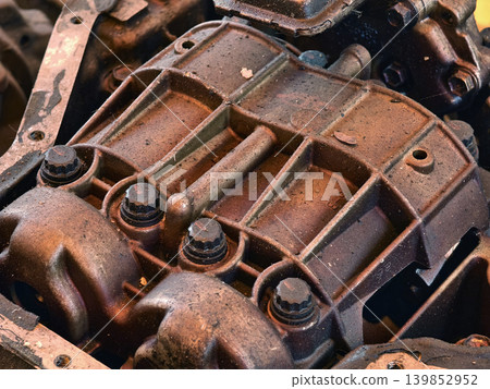 Rusted engine parts and corroded gears scattered across the sandy ground 139852952