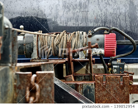 Rust covered winch with coiled rope under tension on the truck 139852954