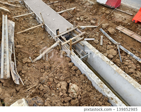 Narrow ditch with reinforcement, waterproof concrete trench bounded by soil and support stakes 139852985