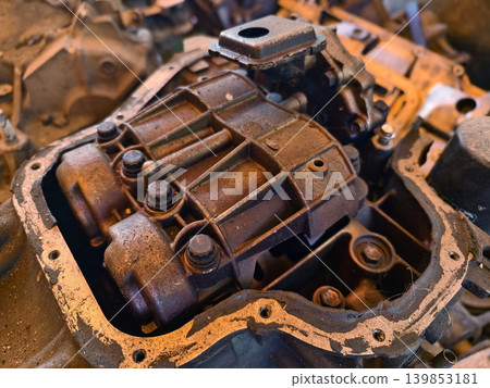 Rusted engine parts and corroded gears scattered across the sandy ground Rusted engine parts and corroded gears scattered across the sandy ground 139853181