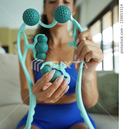 Woman blue sportswear adjusting teal massage roller device Woman blue sportswear adjusting teal massage roller device 139853314