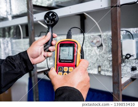 Technician use hand-held anemometer measuring air flowing measurement Technician use hand-held anemometer measuring air flowing measurement 139853410
