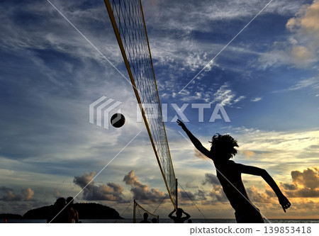 Young people playing beach volleyball by the ocean at sunset Young people playing beach volleyball by the ocean at sunset 139853418