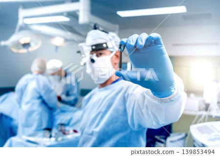 Spinal surgery. Surgeon show polyaxial screw in operating room Spinal surgery. Surgeon show polyaxial screw in operating room 139853494