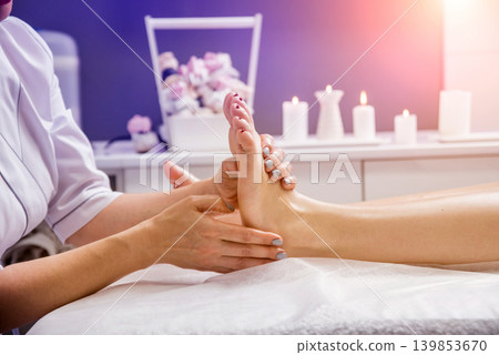 Beautiful young woman enjoying foot massage in spa salon. Cosmetology Beautiful young woman enjoying foot massage in spa salon. Cosmetology 139853670