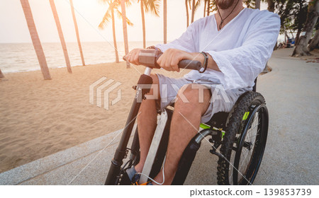 Disabled man in a wheelchair with electric scooter on the beach Disabled man in a wheelchair with electric scooter on the beach 139853739