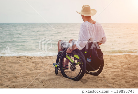 Disabled man in a wheelchair on the beach. 139853745