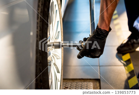 Professional car mechanic working with in auto repair service. Repair of wheels Professional car mechanic working with in auto repair service. Repair of wheels 139853773