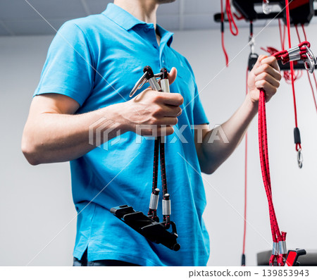 Physiotherapy. Suspension training therapy. Young man doing fitness traction 139853943