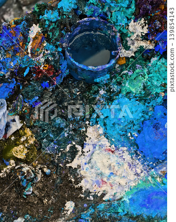 Vibrant messy artist palette covered in glossy paint, scattered brushes and tubes, dried paint Vibrant messy artist palette covered in glossy paint, scattered brushes and tubes, dried paint 139854143