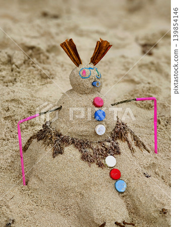 Beach scene delight. Joyful sandy creation adorned with shells and beach accessories Beach scene delight. Joyful sandy creation adorned with shells and beach accessories 139854146