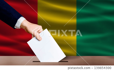 Hand placing a ballot in ballot box with the Guinean flag in the background. Guinea Parliamentary vote 139854300