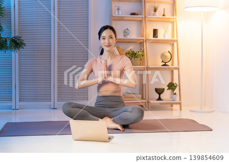 A woman doing yoga at night while watching a video. A woman doing yoga at night while watching a video. 139854609
